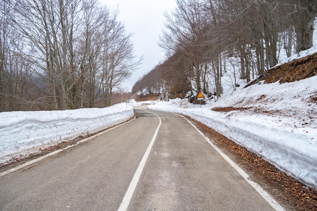 Una strada con la neve sul lato e un cartello che dice "strada a destra"