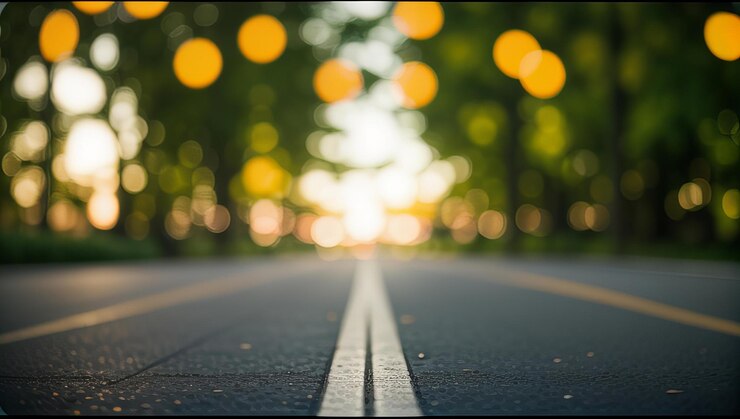 una strada con una linea bianca su di essa e il sole che splende attraverso gli alberi