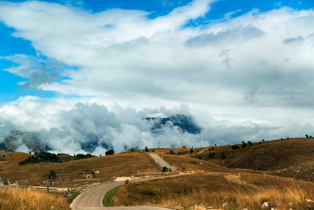 Una strada in campagna con un cupo panorama di nuvole