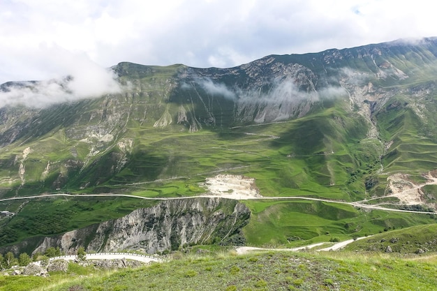 Una strada tra le montagne del Daghestan con grandi montagne sullo sfondo e nuvole Russia