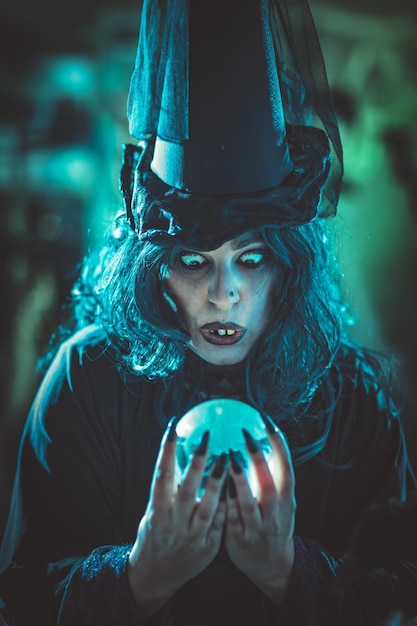 Una strega arrabbiata sta guardando il futuro in una palla magica sopra la pentola con una pozione velenosa.