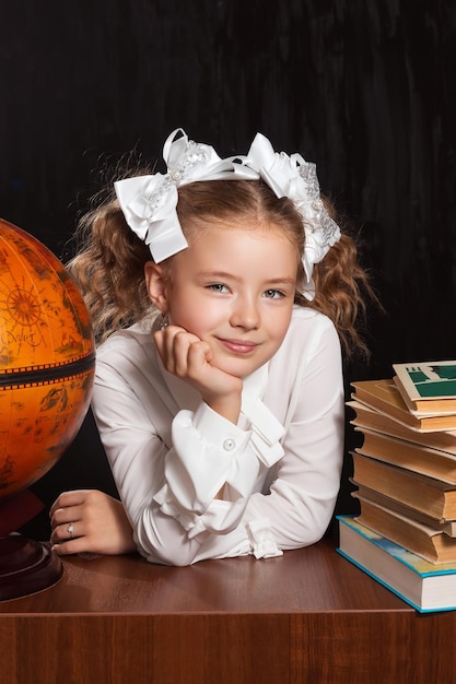 Una studentessa felice a una scrivania tra libri e un globo