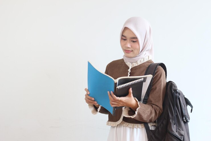 Una studentessa musulmana che studia con libri e zaino su uno sfondo bianco