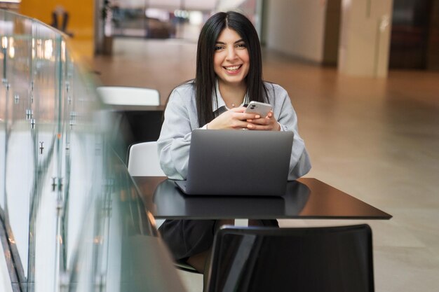 Una studentessa sta scrivendo su un laptop in un centro commerciale