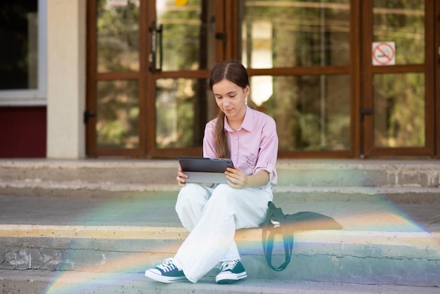 Una studentessa sui gradini della scuola con un gadget in mano Education Generation Z