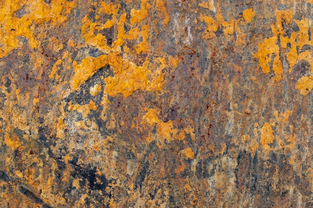 Una superficie metallica ricoperta di pezzi di ruggine arancione.