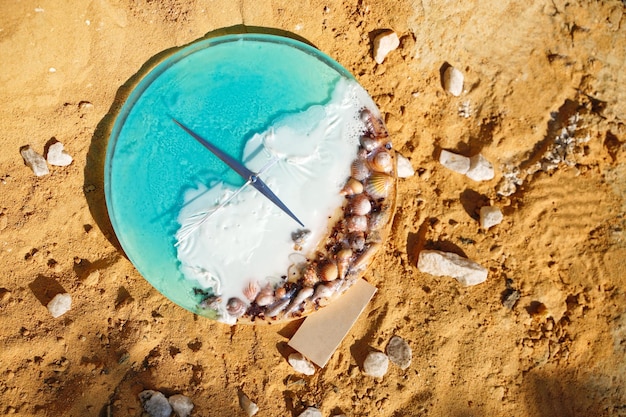 Una sveglia con le conchiglie che si siedono sulla sabbia con il tempo di vacanza dell'acqua Beach Time