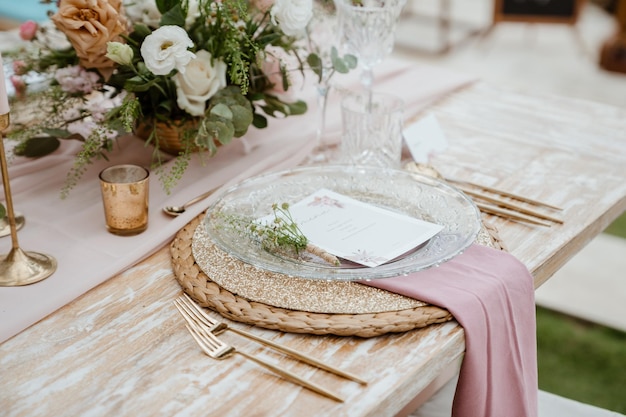 Una tavola apparecchiata per un matrimonio con una tovaglia rosa e un segnaposto con sopra un cartoncino bianco.