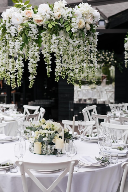 Una tavola apparecchiata per un ricevimento di nozze con fiori bianchi appesi al soffitto.