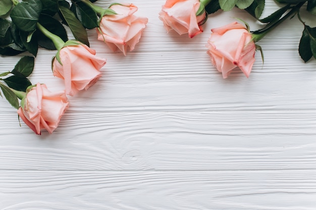 Una tavola di legno bianca con rose rosa.