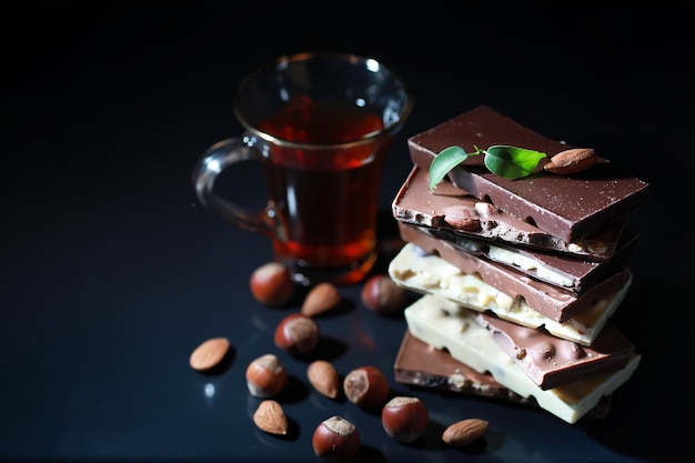 Una tavoletta di cioccolato al latte. Cioccolato al latte fatto in casa con mandorle e fragole secche. Pezzi di cioccolato al latte. Tavoletta di cioccolato al latte senza etichetta. Set di cioccolato con tè.