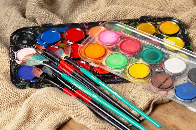 Una tavolozza di colori e pennelli si trova su un tavolo di legno.