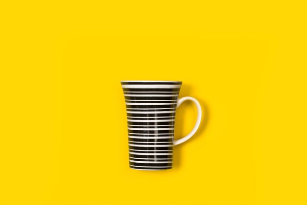 Una tazza a strisce bianche e nere su sfondo giallo con spazio per la copia