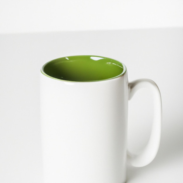 Una tazza bianca con un interno verde è seduta su un tavolo bianco.