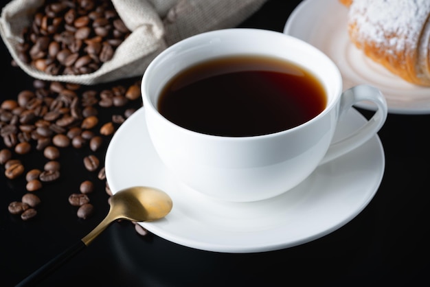 Una tazza bianca di caffè e croissant