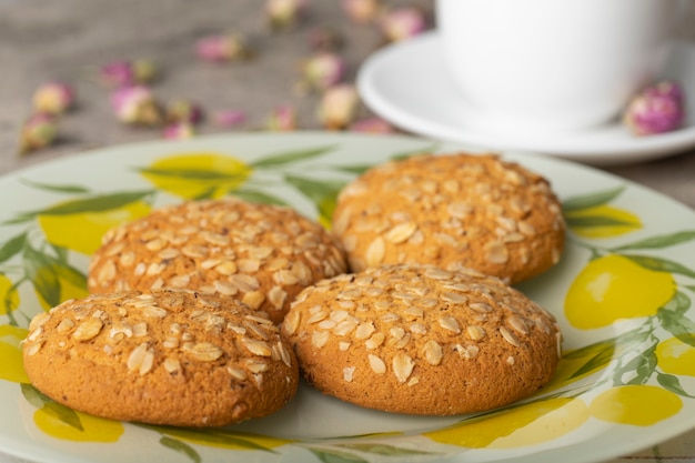 Una tazza bianca di tè caldo con biscotti e boccioli di rosa essiccati.