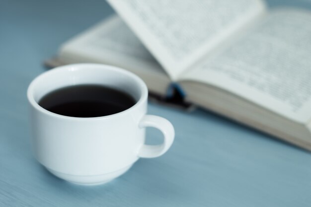 Una tazza di bevanda calda, caffè e un libro aperto.