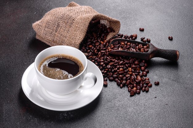 Una tazza di caffè al mattino profumato e fresco per iniziare la giornata in modo allegro. Bella tazza di caffè con caffè su un tavolo scuro