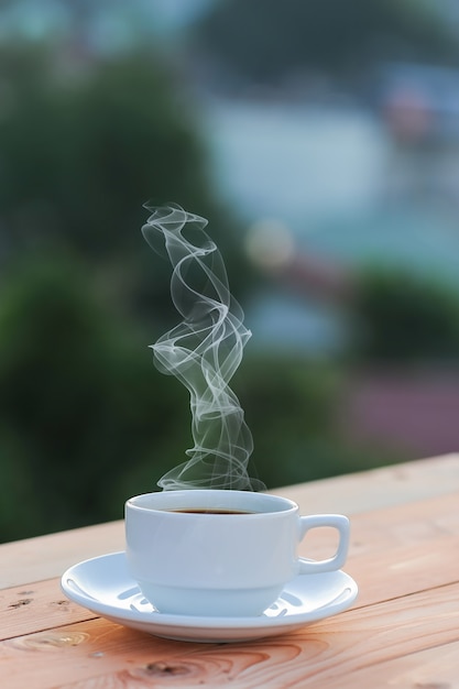 Una tazza di caffè, bevande calde e sigarette sul tavolo al mattino