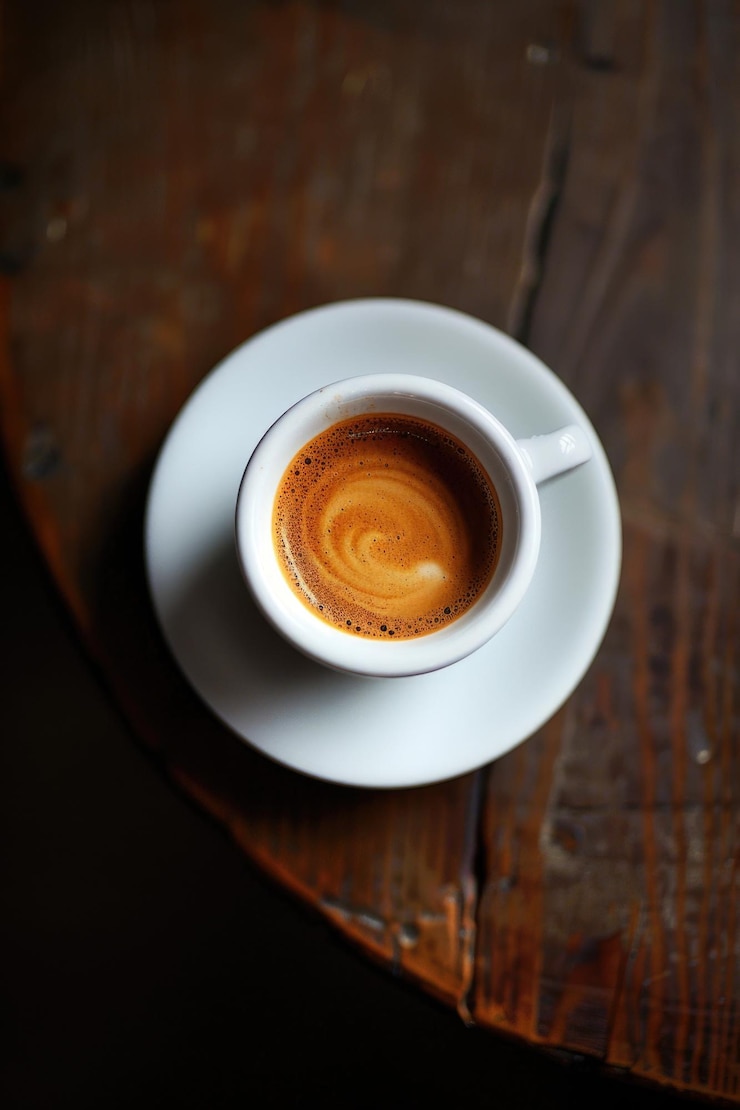Foto una tazza di caffè bianca con un vortice marrone di caffè in esso si siede su un tavolo di legno