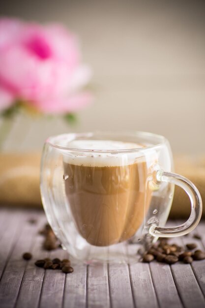 Una tazza di caffè caldo con latte con chicchi di caffè