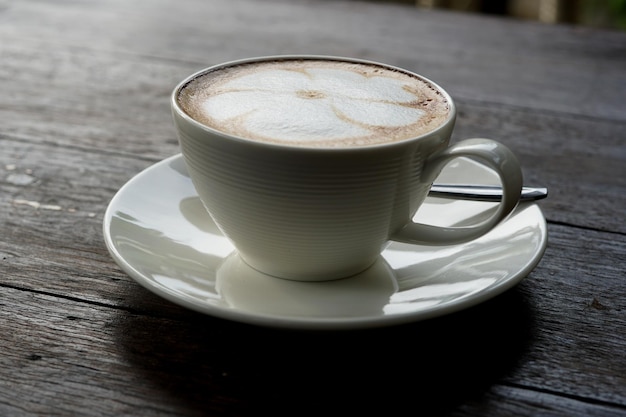 Una tazza di caffè caldo di arte del latte sulla tavola di legno