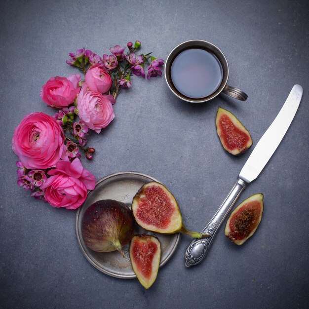 Una tazza di caffè caldo, fichi e fiori.