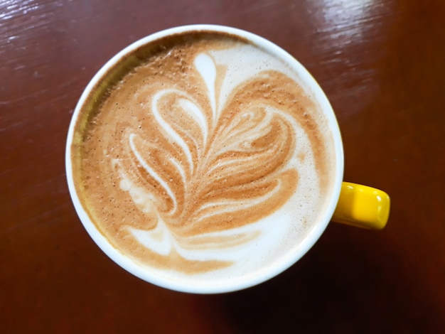 Una tazza di caffè caldo latte sul tavolo di legno.