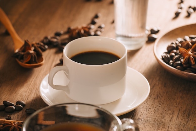 Una tazza di caffè con acqua, chicchi di caffè e tè sulla superficie in legno