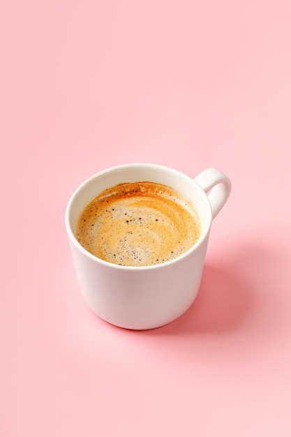 Una tazza di caffè con cappuccino su sfondo rosa Bevanda espresso con schiuma Spazio per la copia