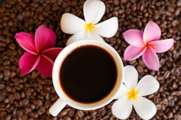 Una tazza di caffè con fiori e un fiore sullo sfondo