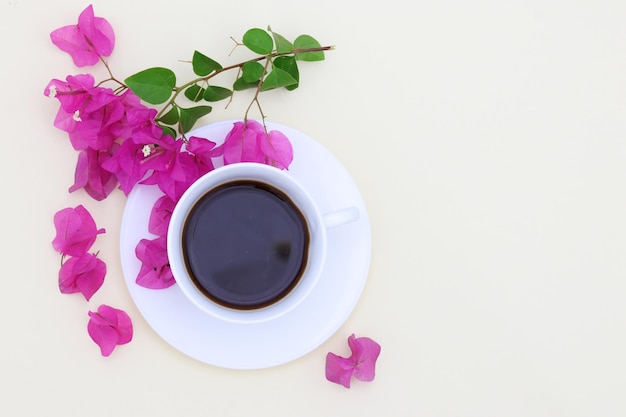 Una tazza di caffè con fiori rosa su sfondo bianco