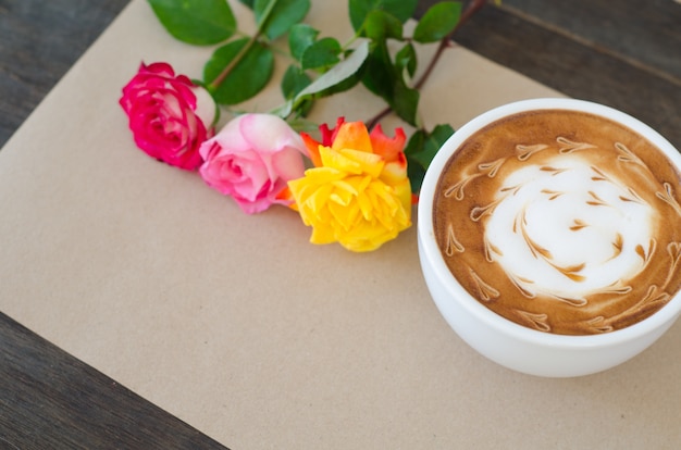 Una tazza di caffè con latte art e rosa su sfondo di carta marrone