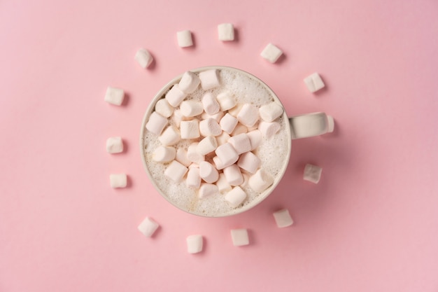 Una tazza di caffè con marshmallow sul muro rosa marshmallow giacciono intorno a forma di orologio