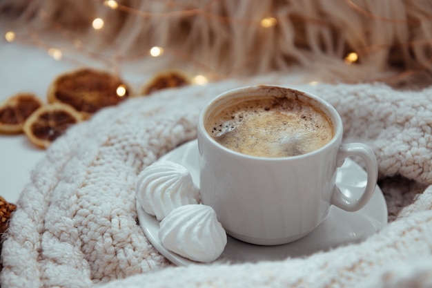 Una tazza di caffè con meringhe e un maglione lavorato a maglia: il concetto di comfort e calore.