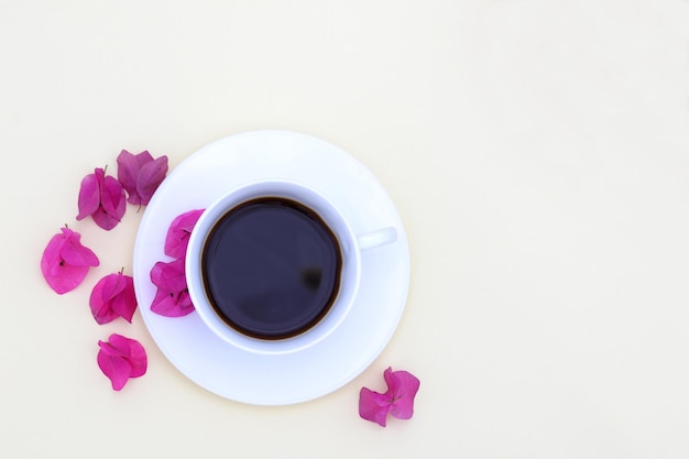 Una tazza di caffè con petali rosa su sfondo giallo