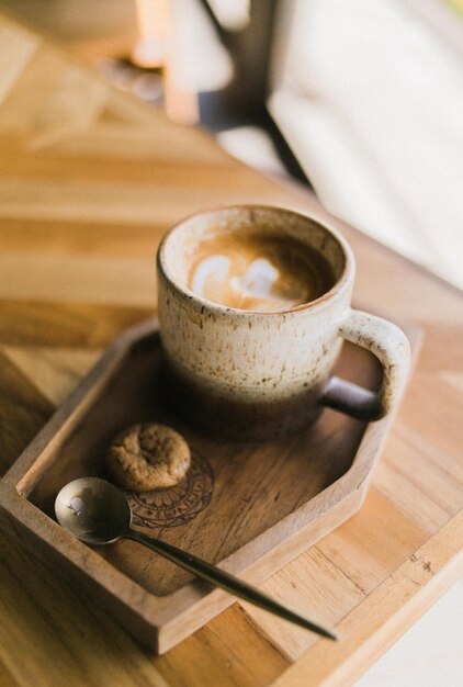 Una tazza di caffè con un biscotto su un vassoio