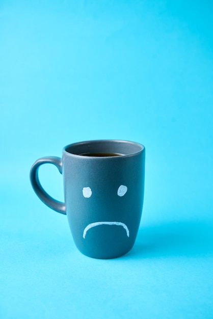 Una tazza di caffè del lunedì blu con una faccia triste.