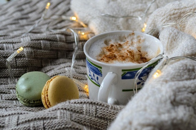 una tazza di caffè e amaretti su un plaid lavorato a maglia