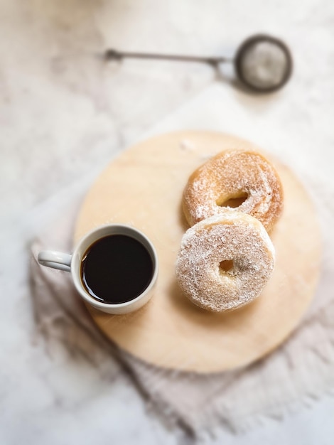 Una tazza di caffè e due ciambelle su una tavola di legno.