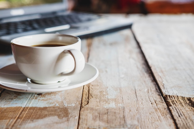 Una tazza di caffè e un computer portatile sulla scrivania