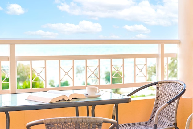 Una tazza di caffè e un libro aperto su un tavolo balcone Vista sullo sfondo del cielo blu e del mare