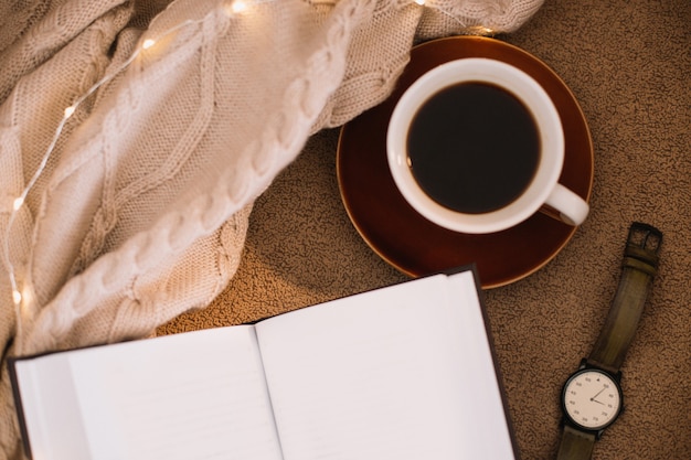 una tazza di caffè e un libro su una lettura a quadri e un concetto di relax a casa