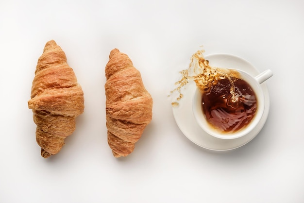 Una tazza di caffè e un paio di croissant su sfondo bianco