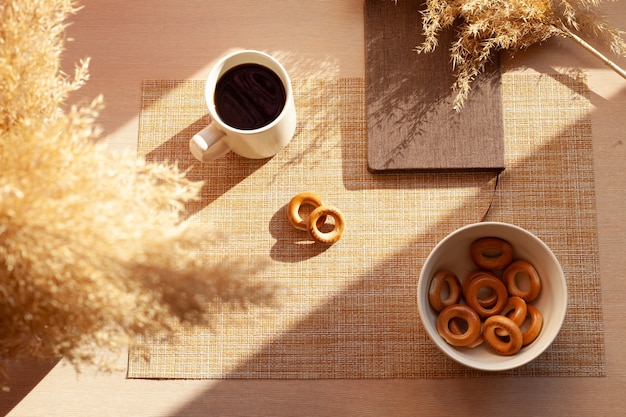 Una tazza di caffè, fiori secchi, barankis, blocco note sulla tavola di legno.