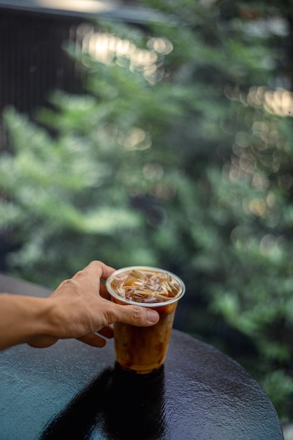 Una tazza di caffè ghiacciato è tenuta da una mano.