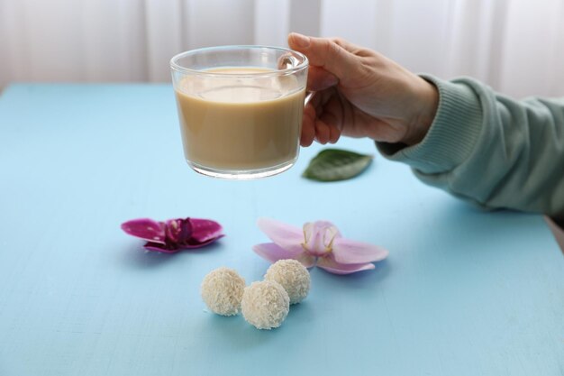 Una tazza di caffè in mano e caramelle sul tavolo