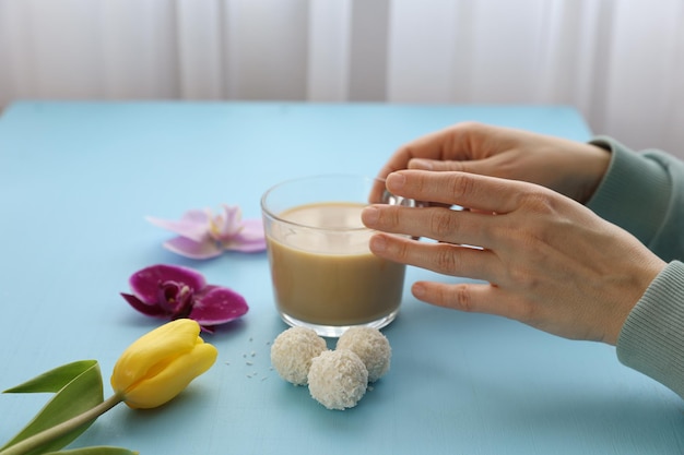 Una tazza di caffè in mano e caramelle sul tavolo