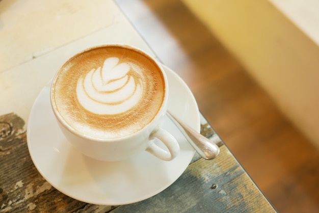 Una tazza di caffè in ritardo con un design a forma di fiore in cima al bar