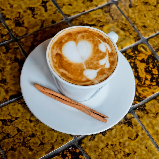 Una tazza di caffè latte e bastoncino di cannella.